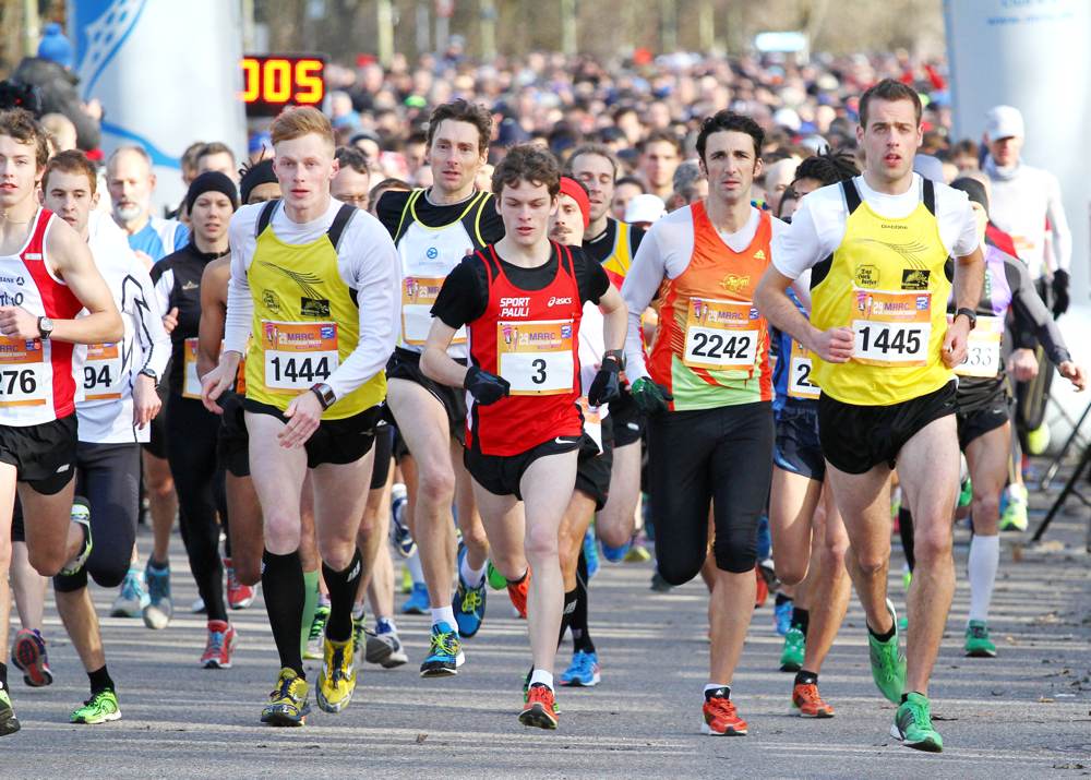 A group of young running competitors wearing jerseys begin to race.