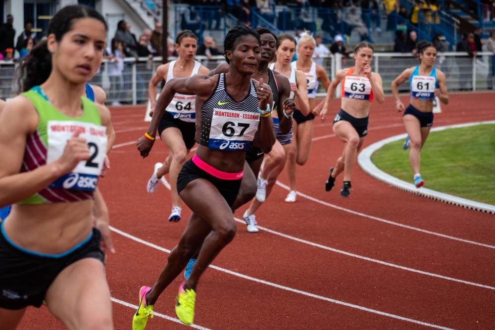 Female track and field competitors race on a track.