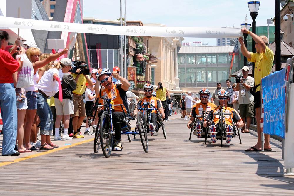 A group of competitors on racing wheelchairs approach the finish line.